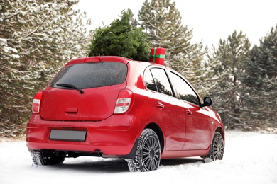 Photo of Car with Christmas tree and gifts in snowy forest on winter day