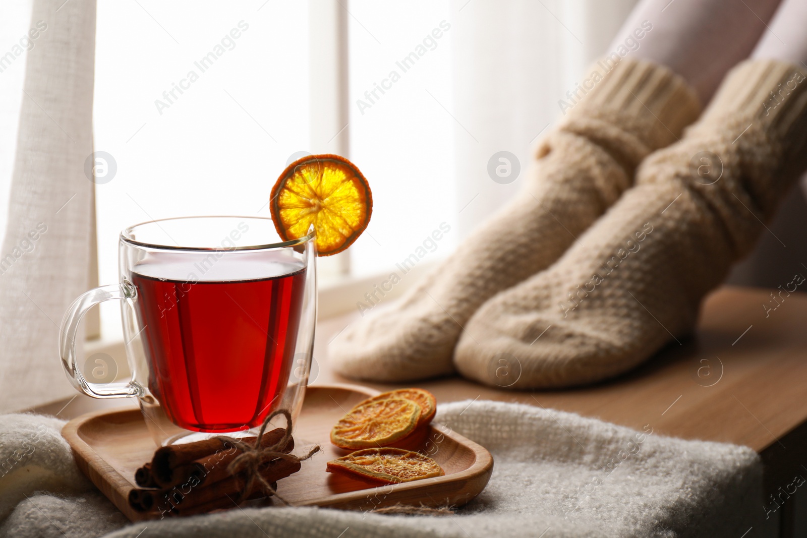 Photo of Woman and cup of hot winter drink near window indoors, closeup