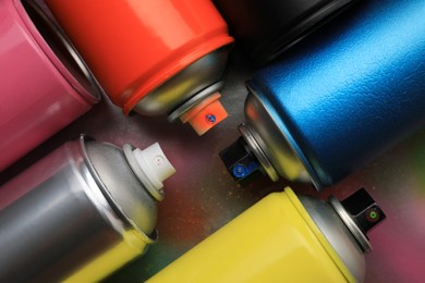 Cans of different graffiti spray paints on color background, flat lay