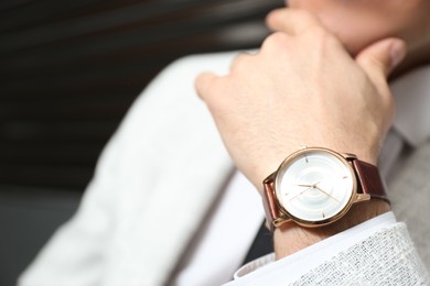 Photo of Businessman with luxury wrist watch on blurred background, closeup