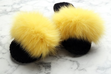 Photo of Pair of soft slippers on white marble background, closeup