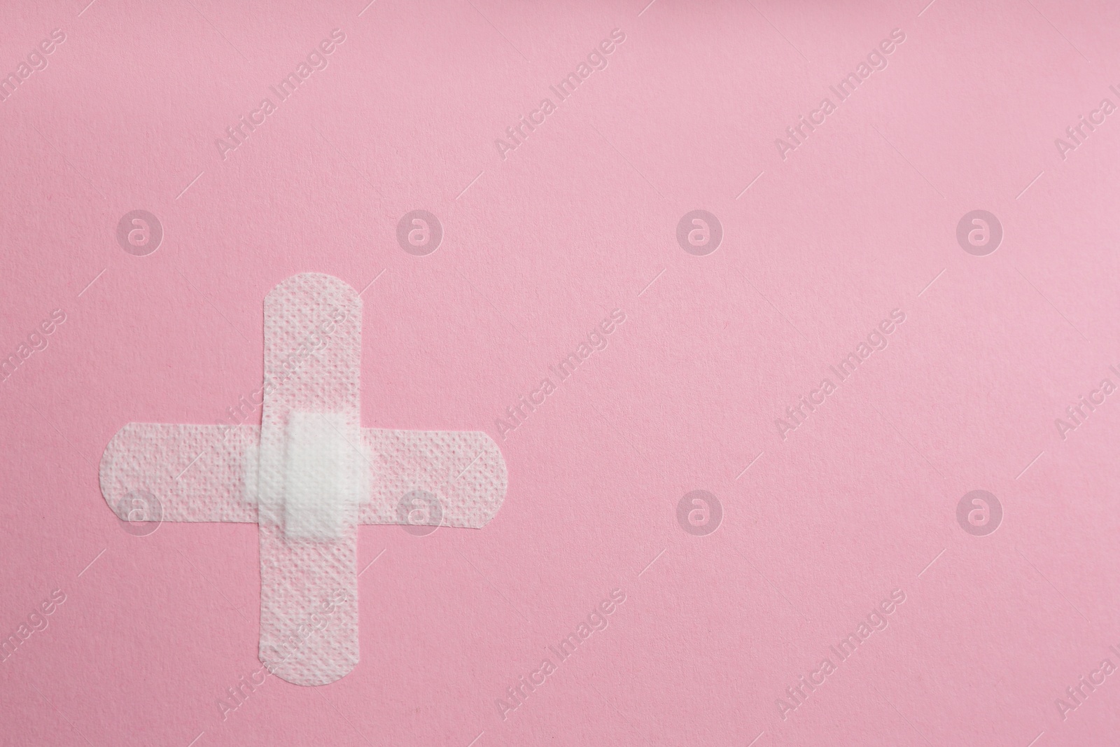Photo of Sticking plasters on pink background, top view. Space for text
