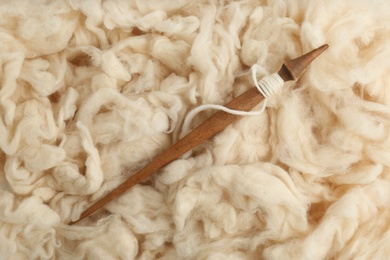 Soft white wool with spindle as background, top view