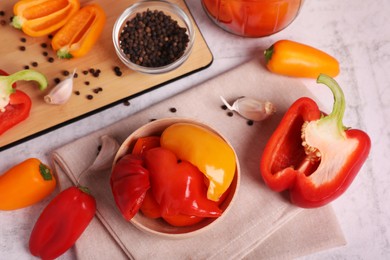 Photo of Bowl with tasty pickled peppers and ingredients on table, flat lay