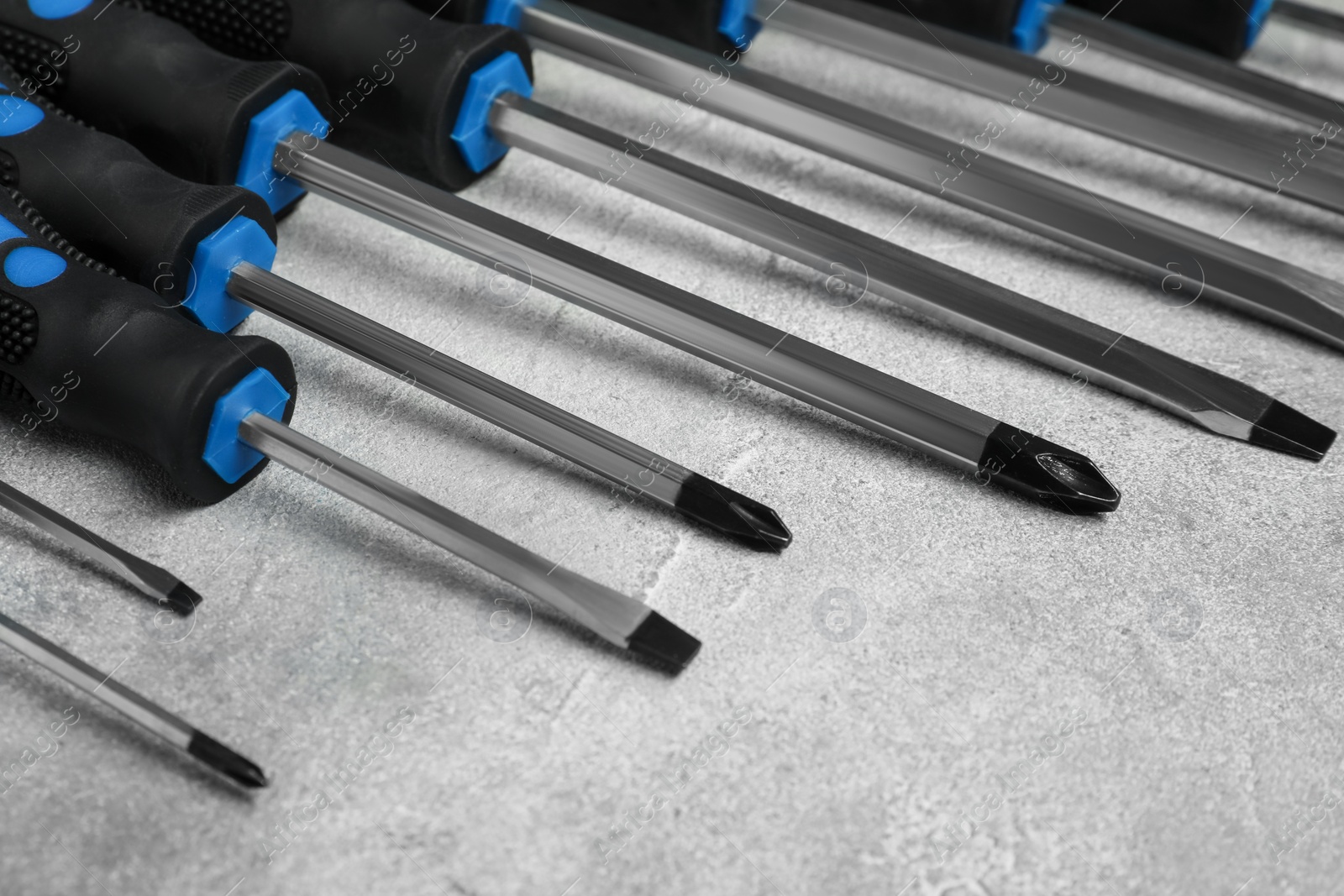 Photo of Set of screwdrivers on grey textured table, closeup