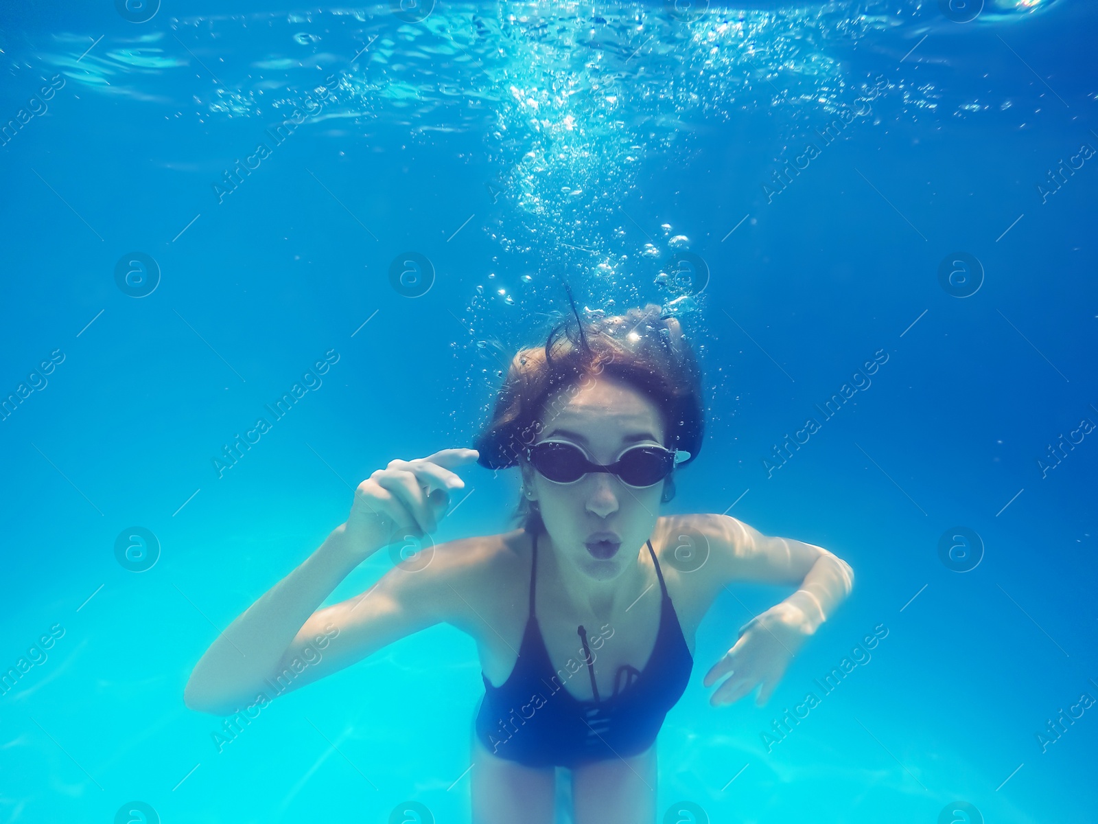 Photo of Beautiful young woman swimming in pool, underwater view