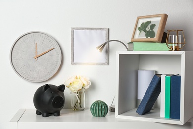 Photo of Cute piggy bank on shelf indoors. Stylish interior element