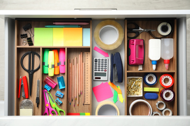 Photo of Different stationery in open desk drawer, top view