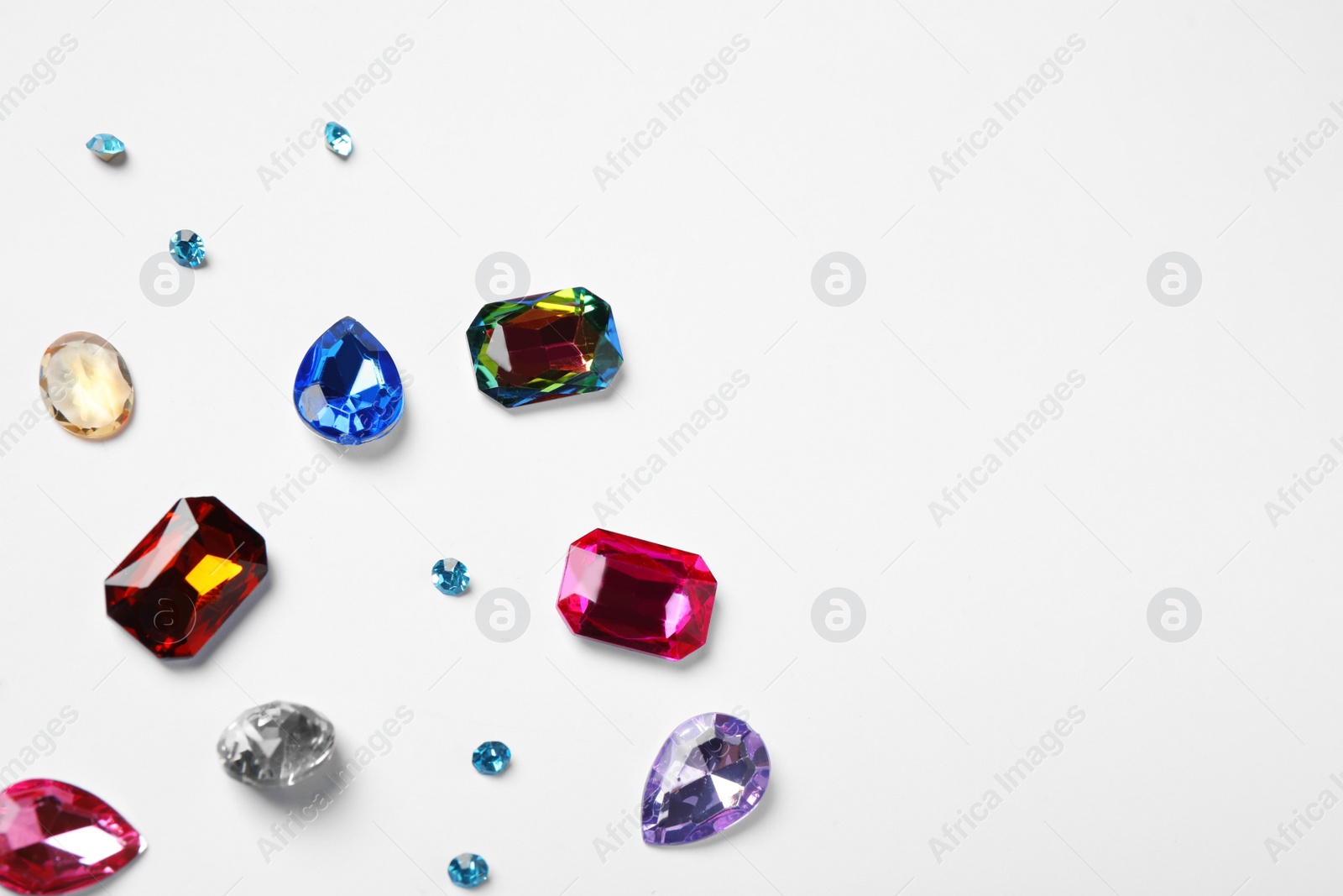 Photo of Different beautiful gemstones on white background, top view