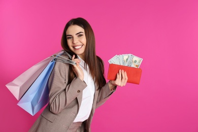 Young woman with money and shopping bags on color background. Space for text