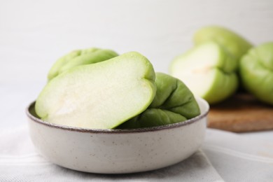 Photo of Cut and whole chayote in bowl on table, closeup