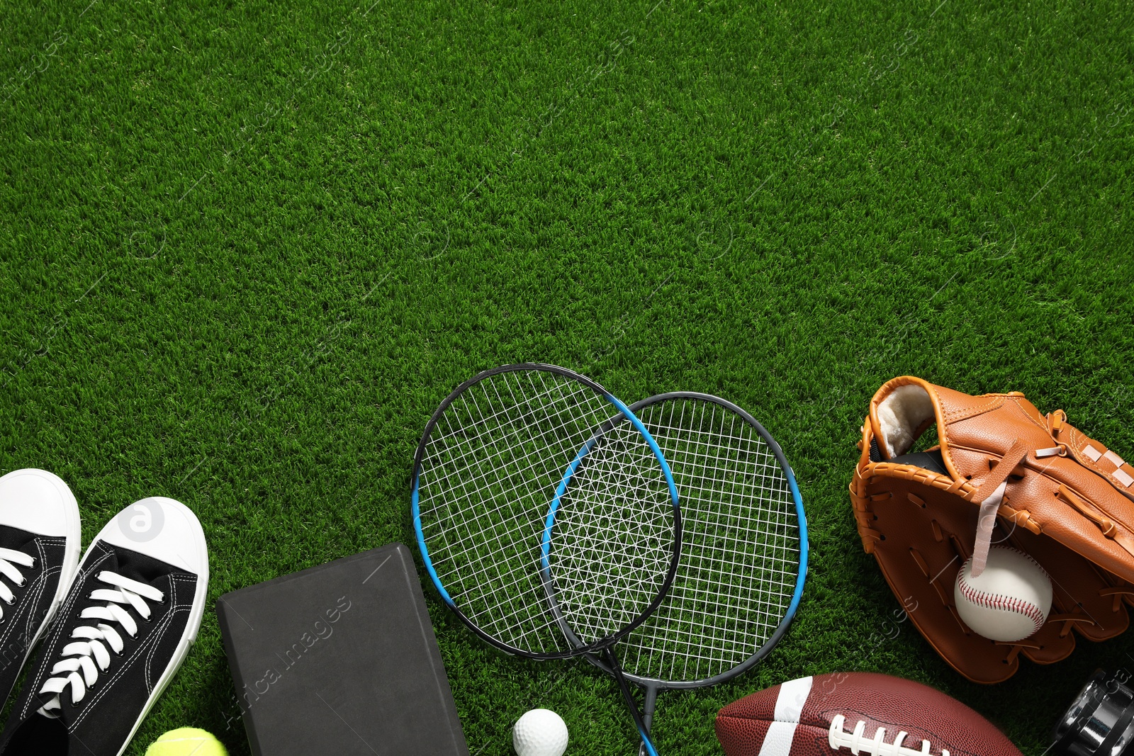 Photo of Different sports equipment on green grass, flat lay. Space for text