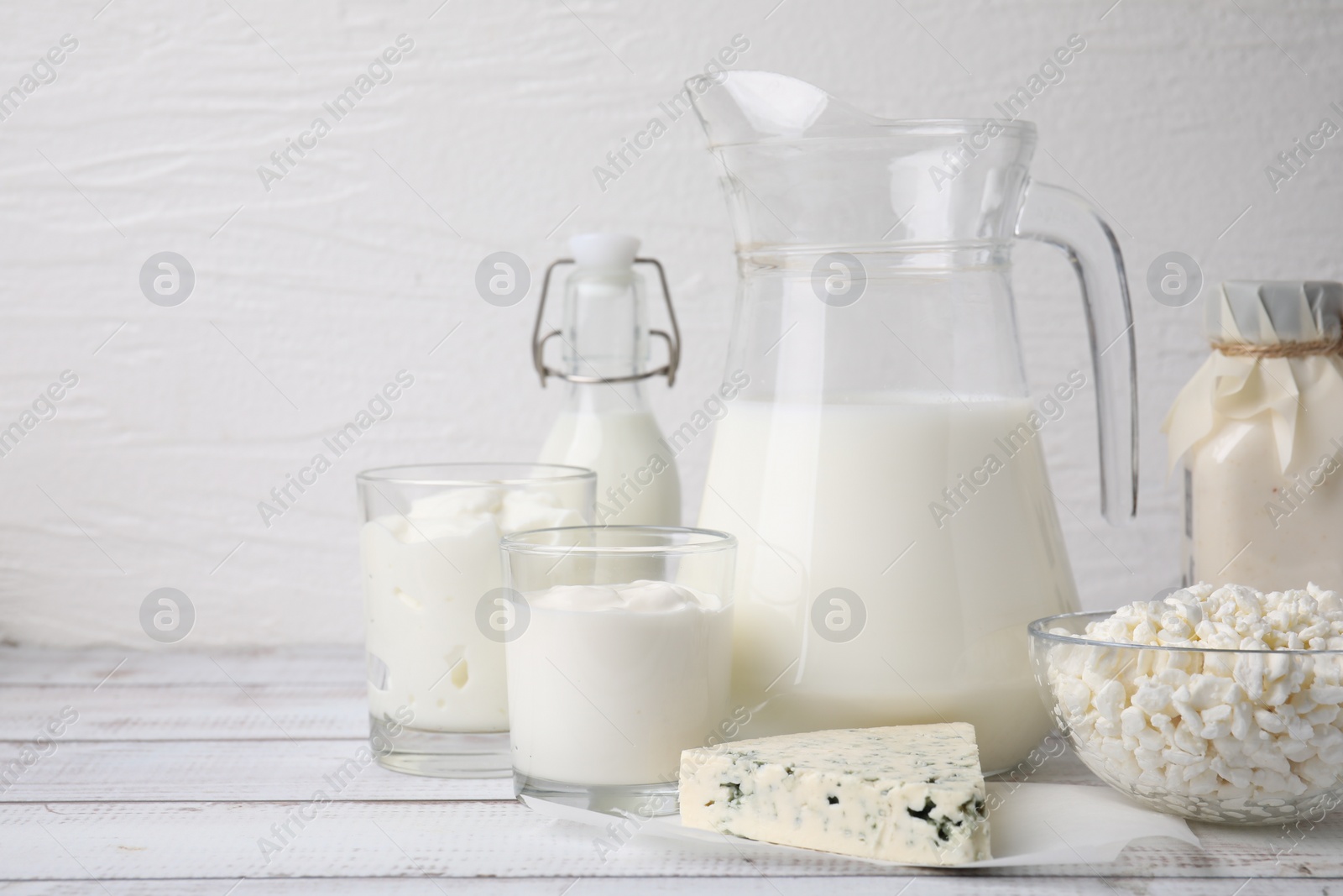 Photo of Different fresh dairy products on white wooden table. Space for text