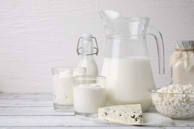 Photo of Different fresh dairy products on white wooden table. Space for text