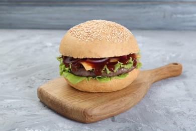 Photo of Delicious cheeseburger with lettuce, onion, ketchup and patty on grey table, closeup