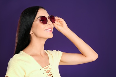 Photo of Beautiful woman wearing sunglasses on purple background