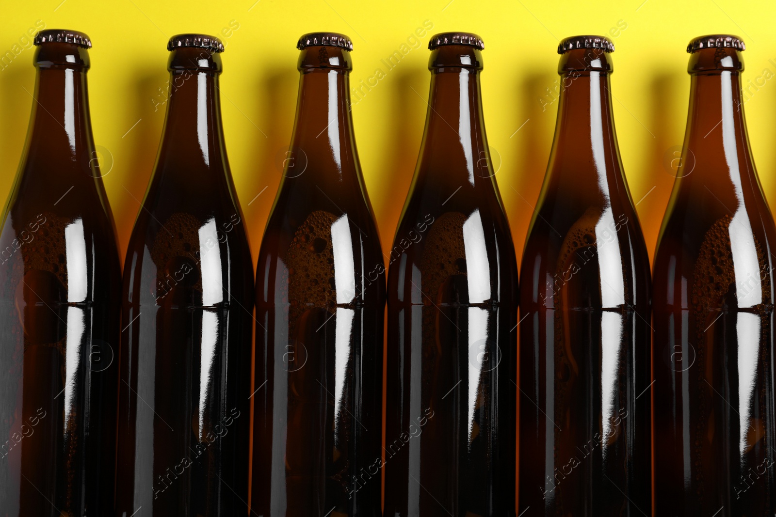 Photo of Bottles of beer on yellow background, flat lay