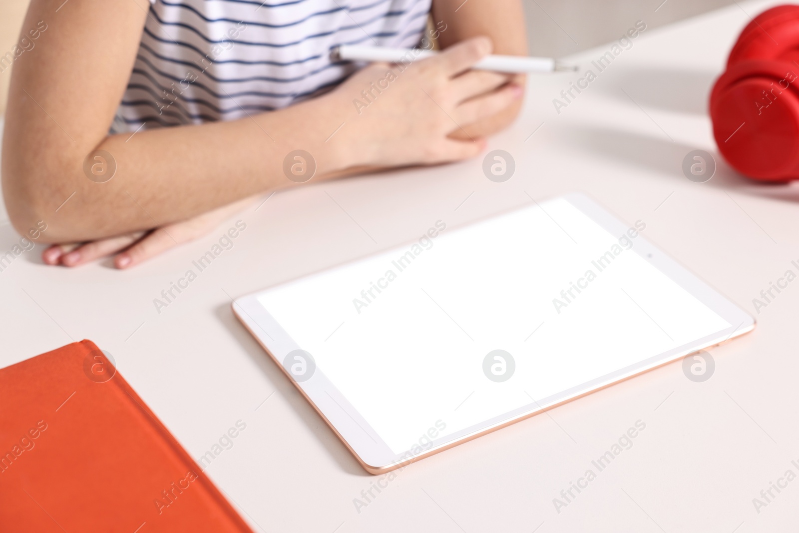 Photo of E-learning. Girl using tablet for studying online at table indoors, closeup