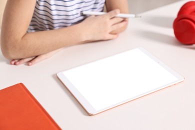 Photo of E-learning. Girl using tablet for studying online at table indoors, closeup