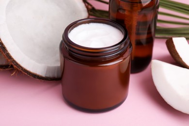 Different hand care cosmetic products and coconut on pink background, closeup