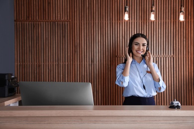 Portrait of receptionist with headset at desk in lobby