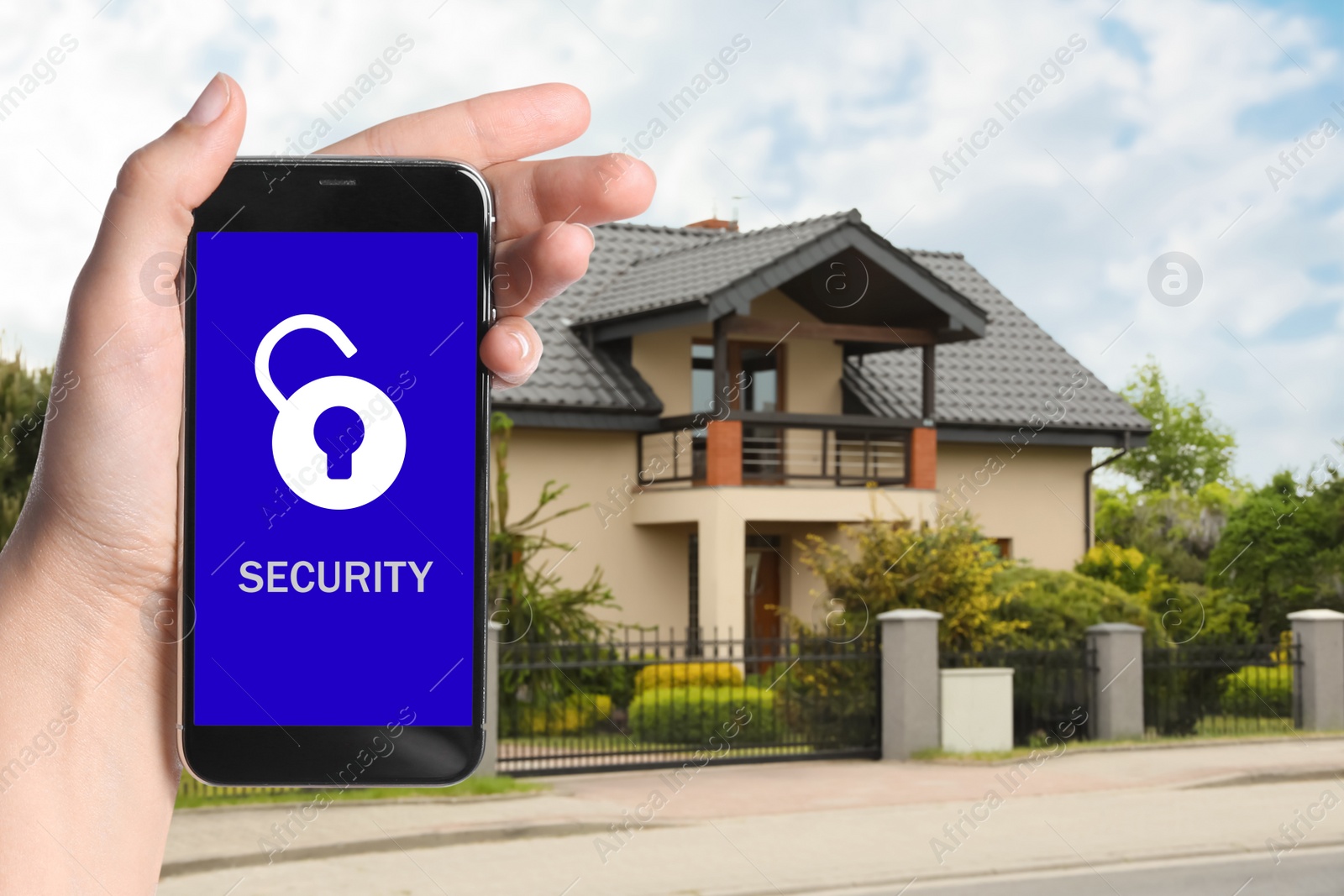 Image of Home security system. Woman with smartphone near her house outdoors, closeup