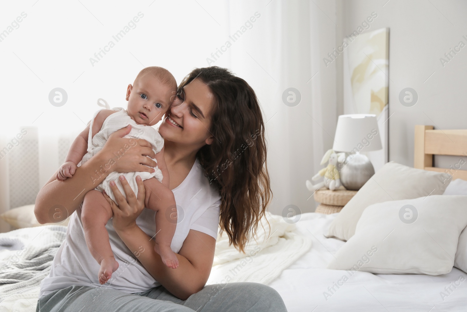 Photo of Happy young mother with her cute baby on bed at home