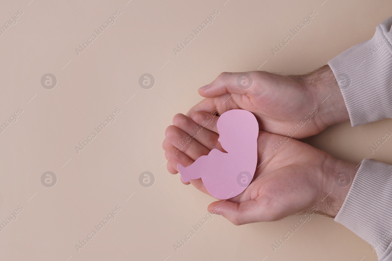 Photo of Female health. Man holding newborn paper figure on beige background, top view with space for text