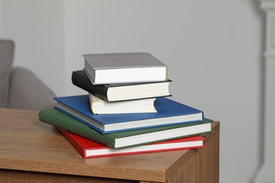 Stack of hardcover books on wooden table indoors