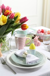 Photo of Easter celebration. Festive table setting with beautiful flowers and painted eggs