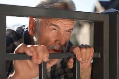 Photo of Concept of private life. Curious senior man spying on neighbours over fence outdoors, closeup