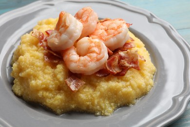 Plate with fresh tasty shrimps, bacon and grits on light blue wooden table, closeup