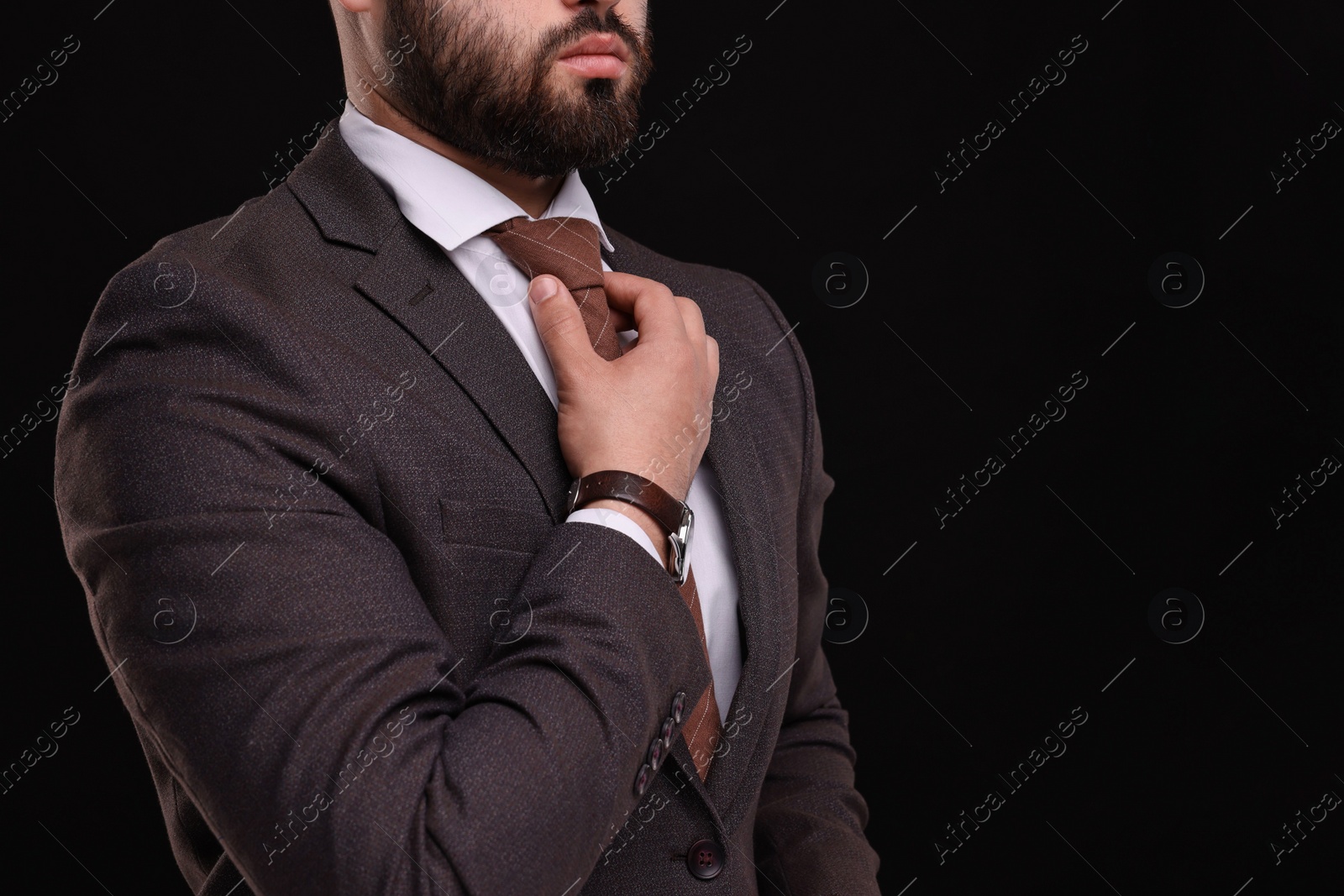 Photo of Businessman in suit and necktie on black background, closeup. Space for text