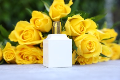 Perfume and beautiful bouquet of yellow roses on light table