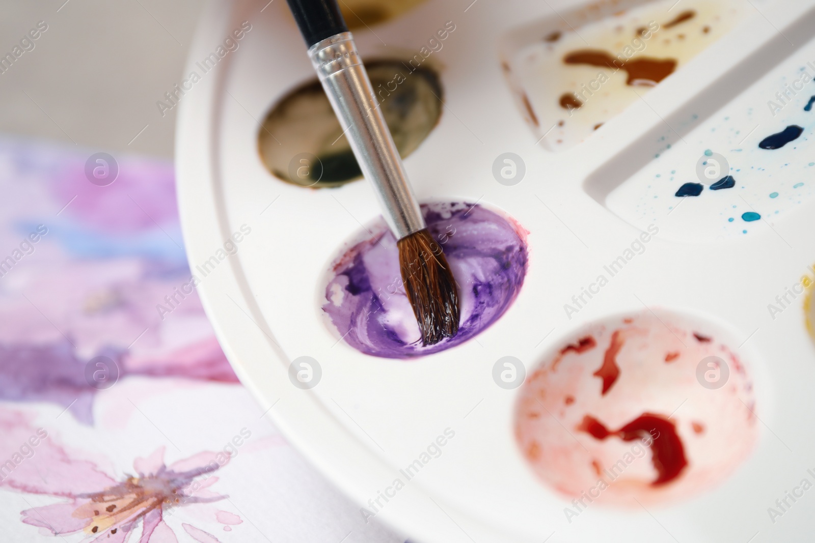 Photo of Brush and palette with watercolor paints, closeup