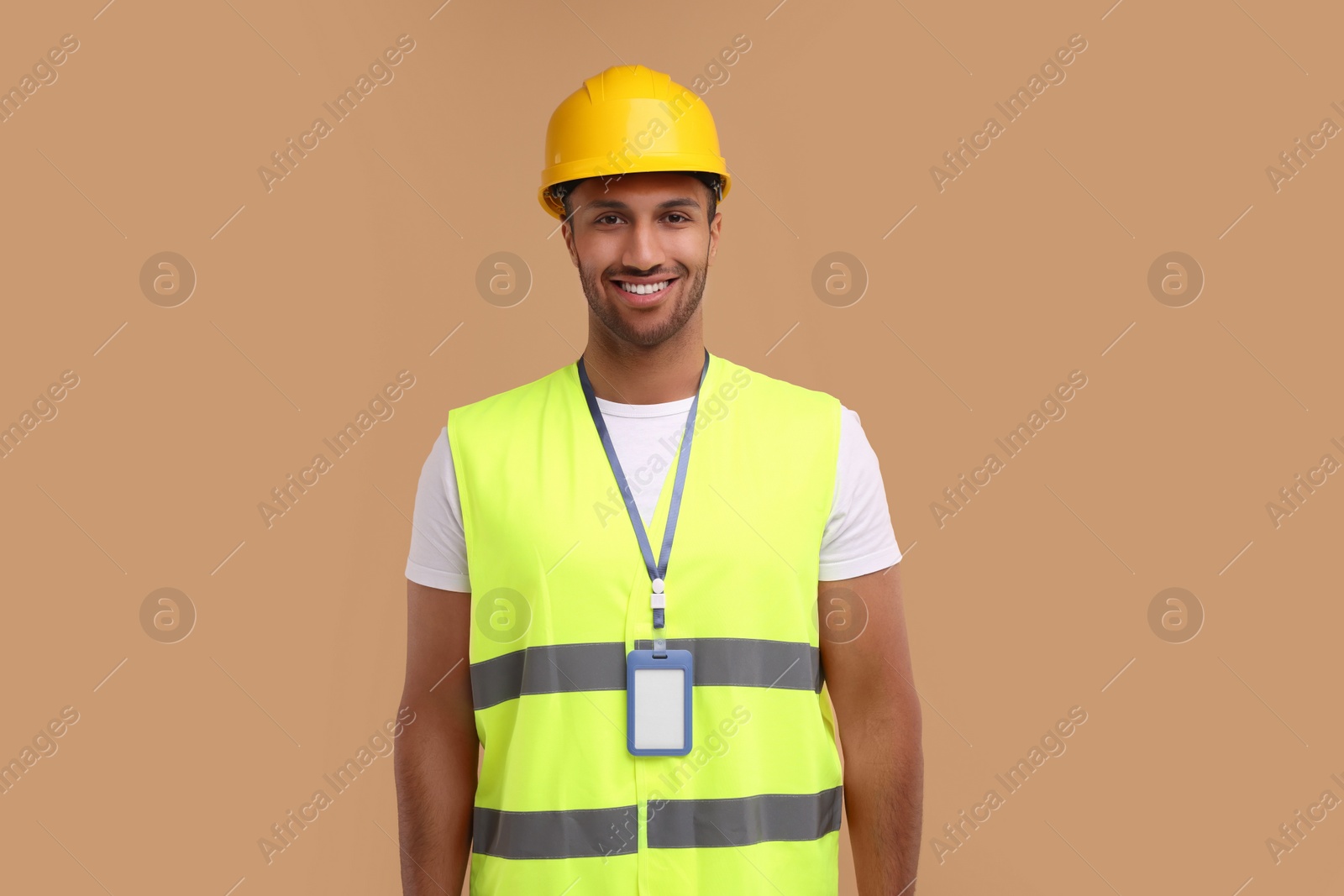 Photo of Engineer with hard hat and badge on beige background