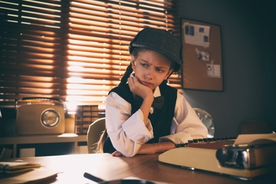 Photo of Cute little detective at table in office
