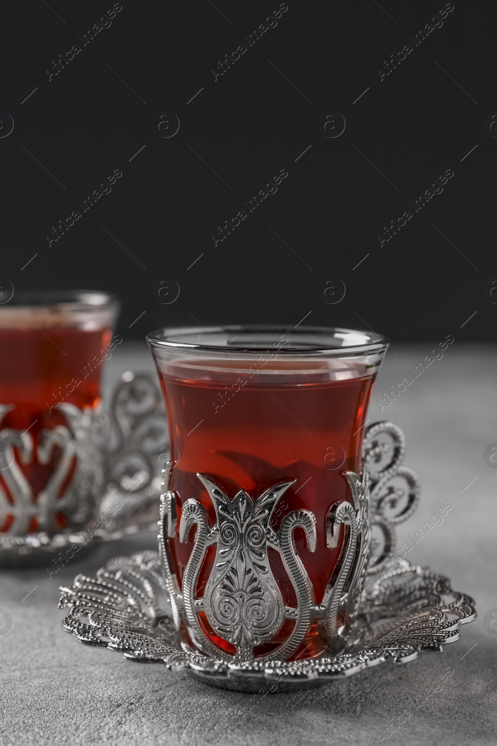 Photo of Glasses of traditional Turkish tea in vintage holders on light grey table