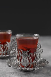 Glasses of traditional Turkish tea in vintage holders on light grey table