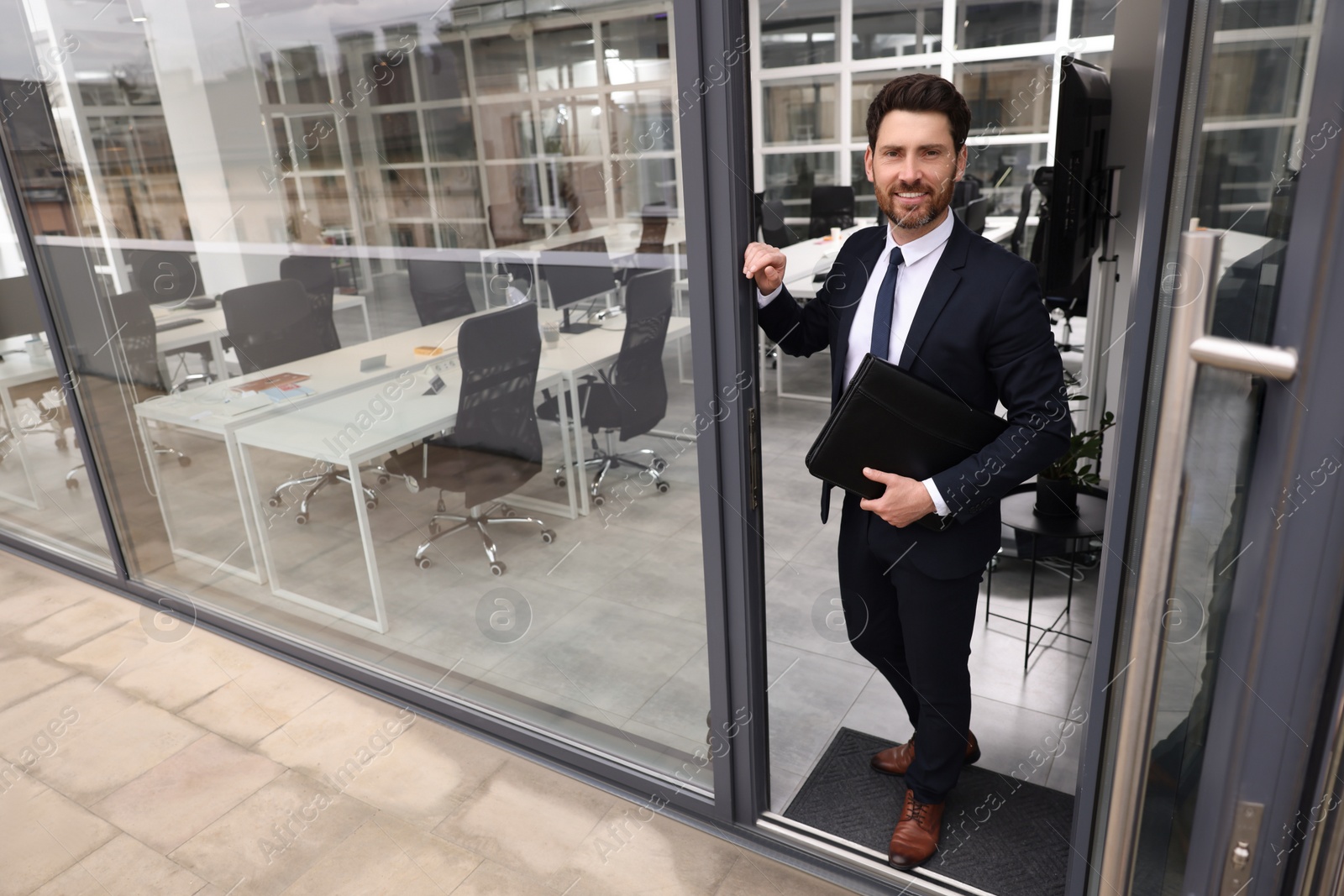 Photo of Happy real estate agent with leather portfolio in office