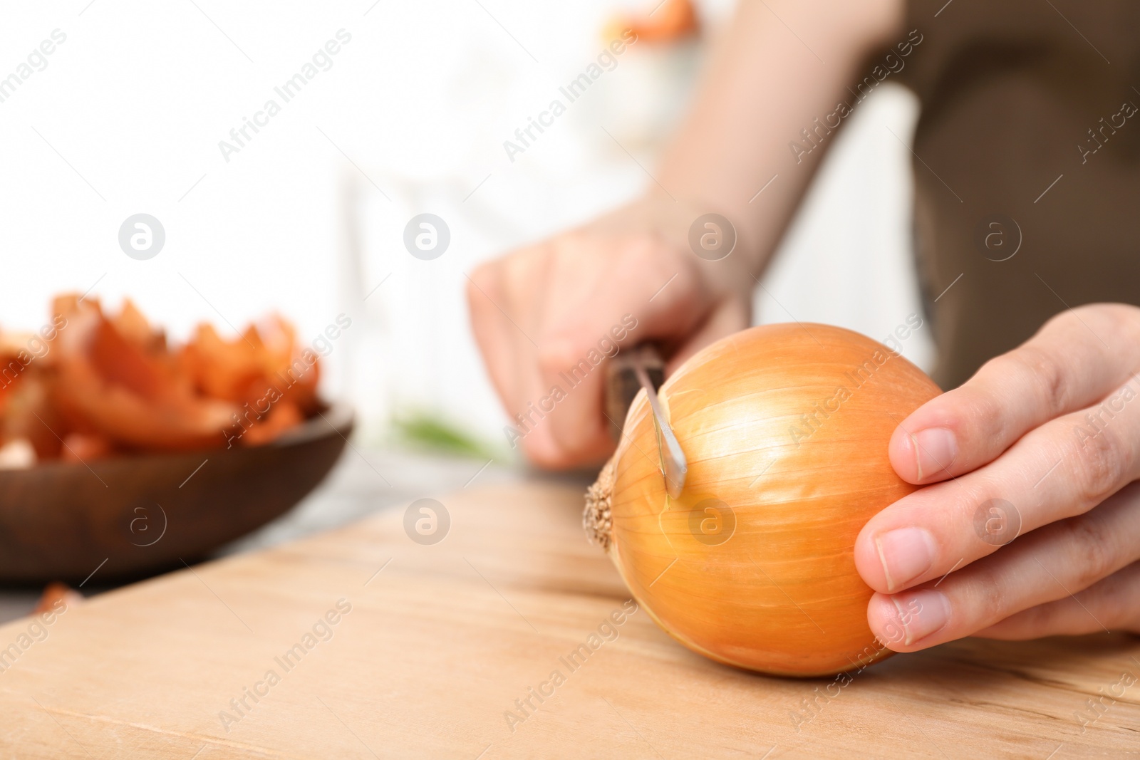 Photo of Woman cutting onion on wooden board, closeup