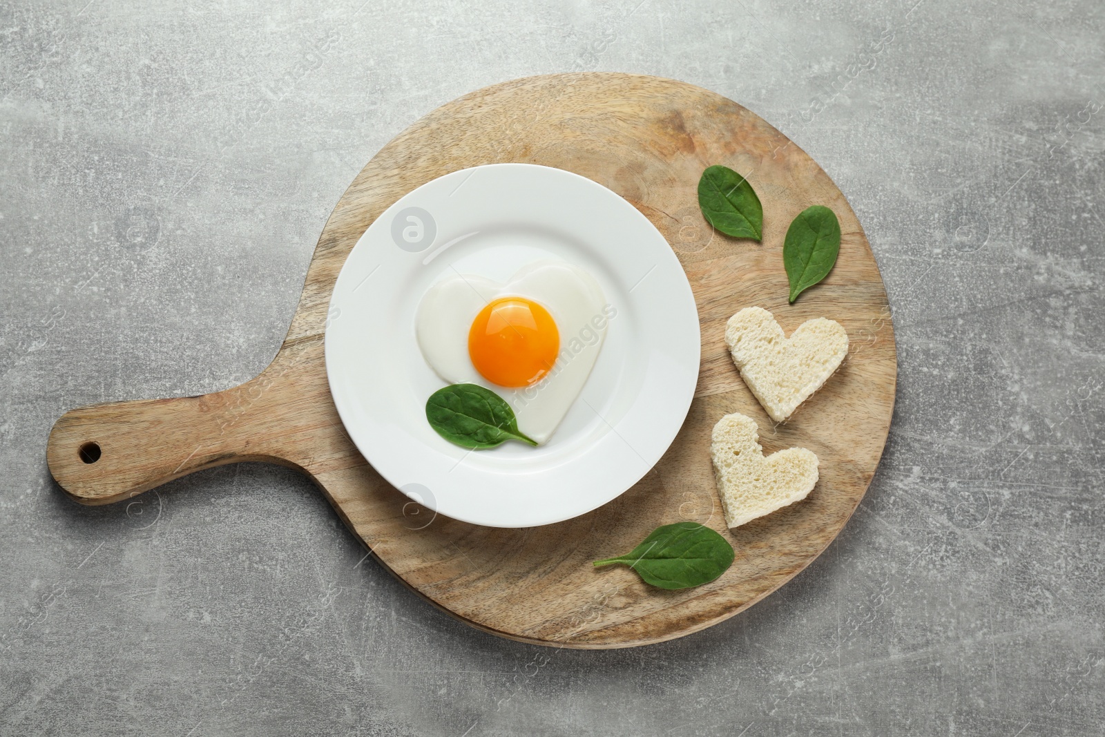 Photo of Romantic breakfast with heart shaped fried egg served on light grey table, top view