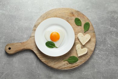 Photo of Romantic breakfast with heart shaped fried egg served on light grey table, top view