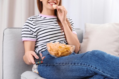 Photo of Woman with bowl of chips on couch, closeup. Watching TV