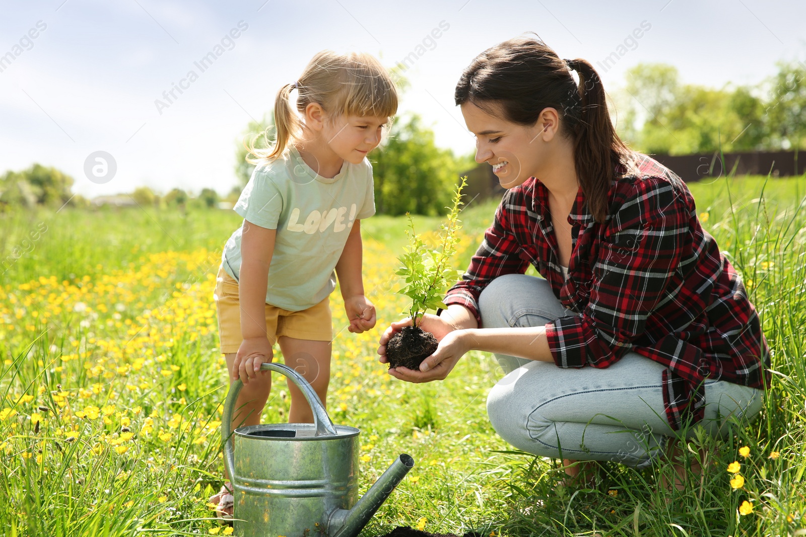 Photo of Mother and her daughter planting tree together outdoors