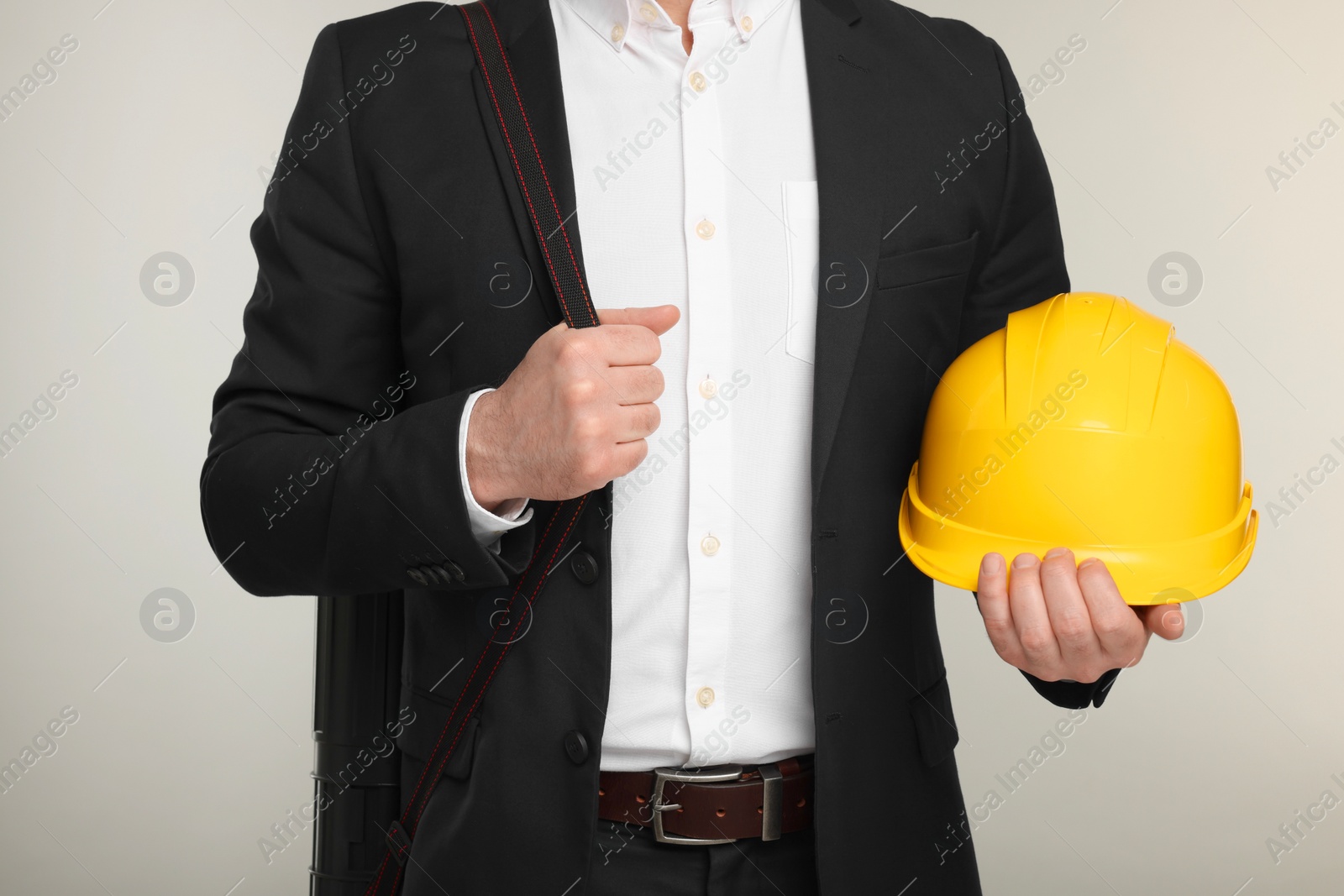 Photo of Architect with drawing tube and hard hat on gray background, closeup