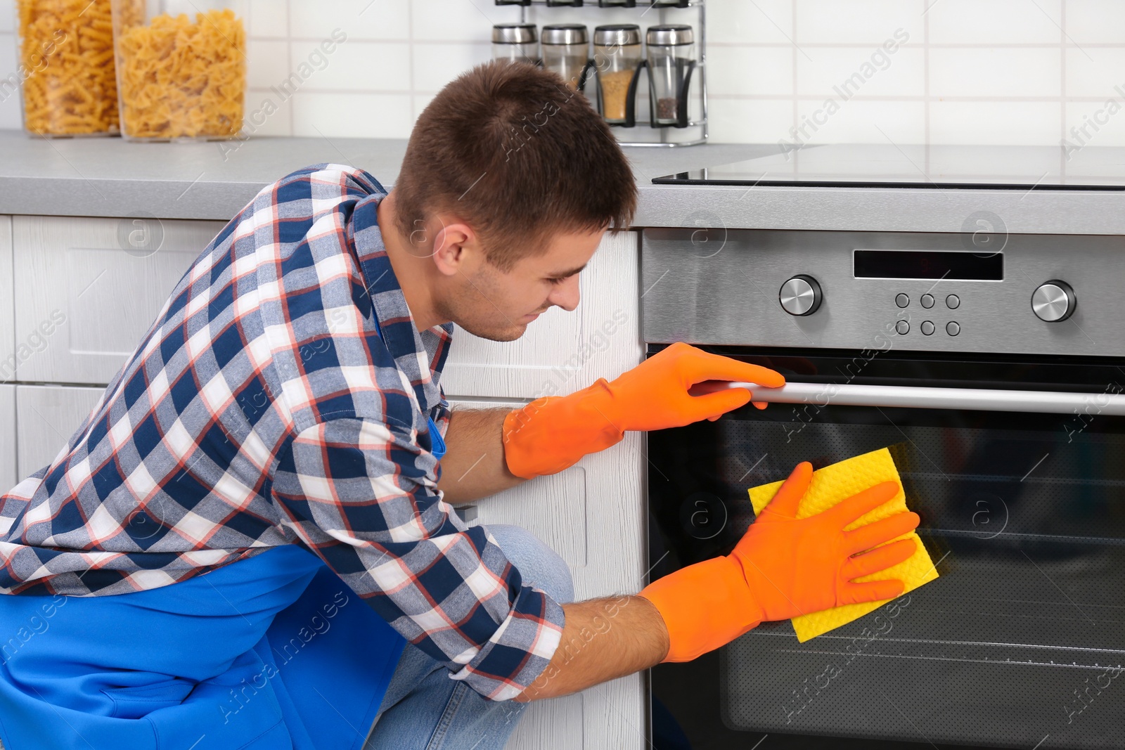 Photo of Man cleaning kitchen oven with rag in house