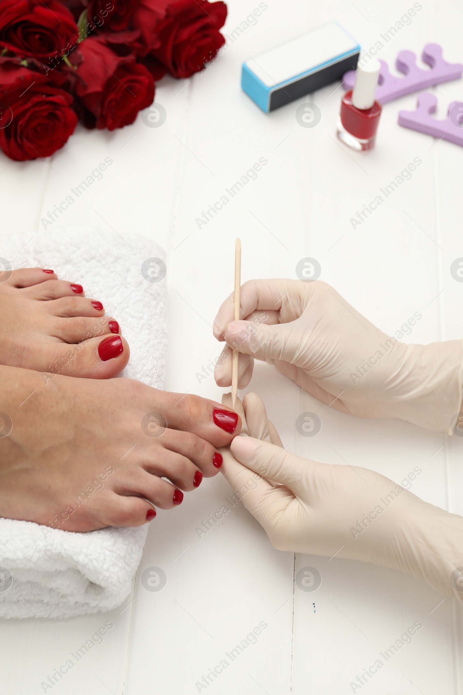 Photo of Pedicurist working with client`s toenails in beauty salon, closeup