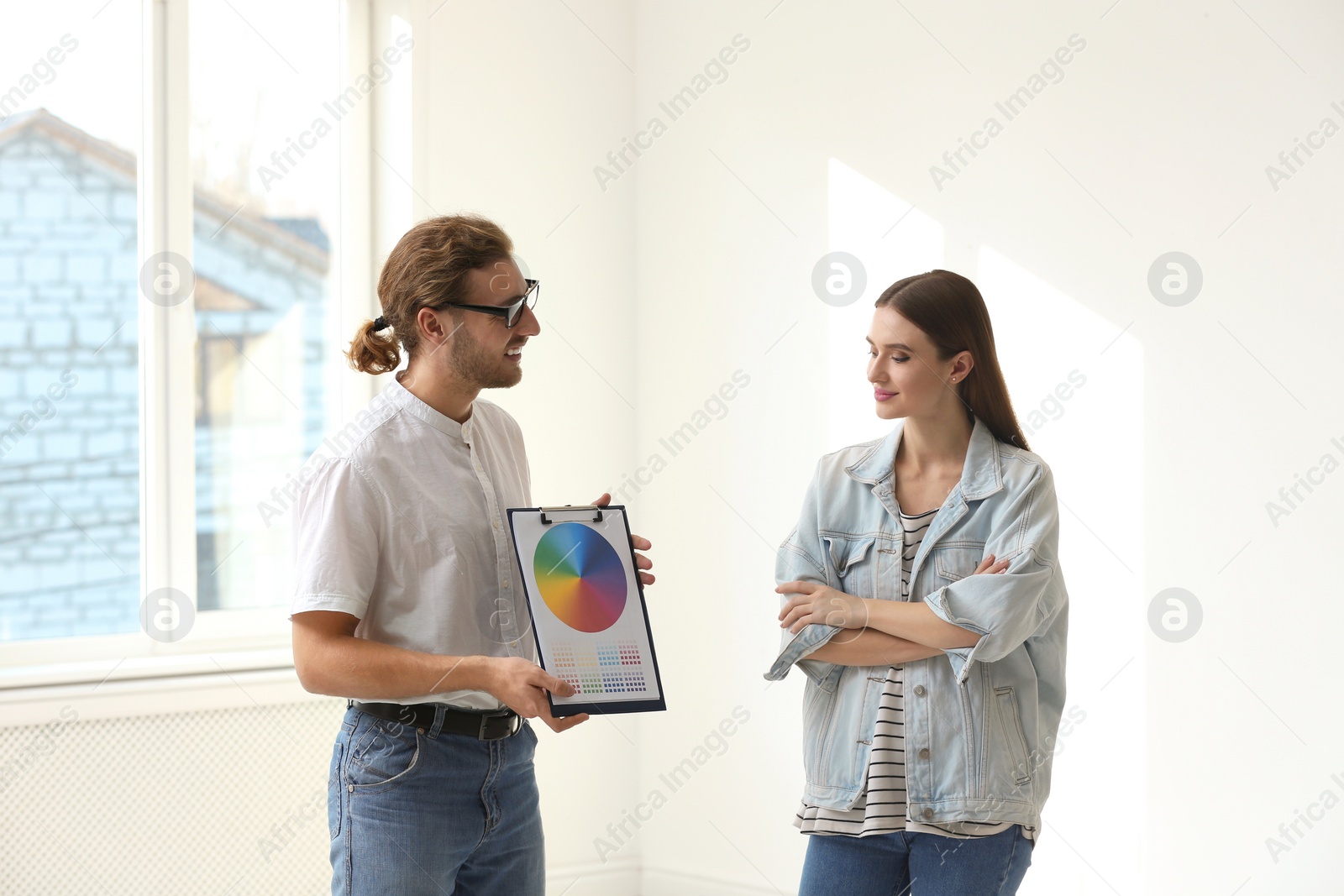 Photo of Professional interior designer consulting woman in empty apartment