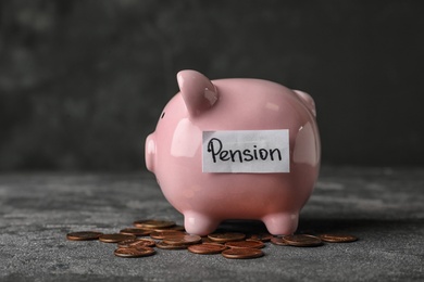 Piggy bank with word PENSION and coins on table